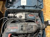 a corded drill in a case on the floor next to other tools