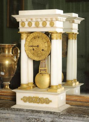 une horloge posée sur une table à côté d'un vase