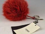 une boule de fourrure rouge accrochée à un porte-clés, avec une étiquette