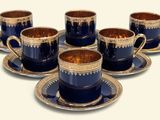 six tasses et soucoupes sont posées sur une soucoupe, sur une surface blanche