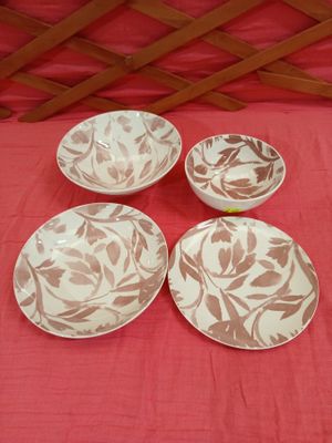four white and brown plates sitting on top of a red cloth