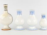 three vases and a bottle sitting on a table