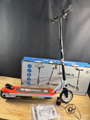 une trottinette électrique posée sur une table en bois, à côté d'une boîte