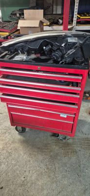 une boîte à outils rouge avec des outils posés dessus, dans un garage