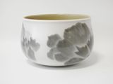 un bol blanc orné de fleurs grises, posé sur une surface blanche