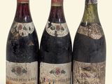 trois bouteilles de vin posées les unes à côté des autres sur une surface blanche