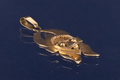 un pendentif en or orné d'un œil, sur un fond bleu