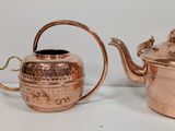 two copper teapots sitting next to each other on a table