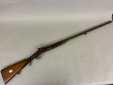 un fusil posé sur une table, dans lequel est enfoncé un couteau