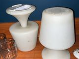 a table with a lamp, a cup, and a cell phone on it
