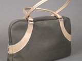 grey and gold leather handbag with strap on grey background