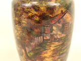 a vase with a painting of a house on it