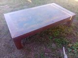une table basse avec un plateau en verre posée dans l'herbe