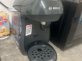 a coffee maker sitting on the floor next to a refrigerator