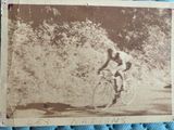 an old photo of a man riding a bike down a road