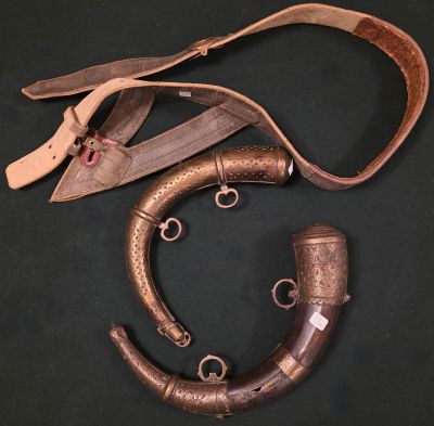 une vieille paire de cornes et une lanière en cuir sur fond noir