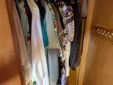 une armoire contenant des vêtements suspendus, dans une pièce