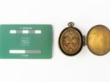 a green credit card and a gold pocket watch on a white surface
