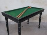 a pool table with two cues on it and a ball on the table