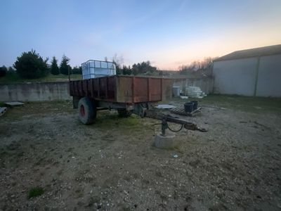 un camion garé sur un terrain en terre battue près d'une clôture