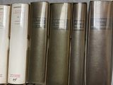 several old books are lined up on a shelf in a library