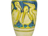 a yellow vase with birds on it on a white surface