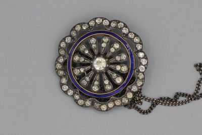 une broche bleue et blanche entourée d'une chaîne