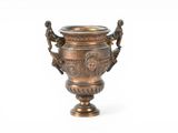 a bronze vase that is sitting on a white surface