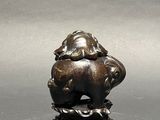 a small bronze statue of a dog on a tree stump
