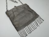 chainmail purse with silver beads and chains on a white surface