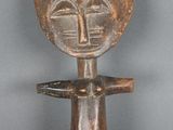 une vieille figurine en bois avec un visage sur la tête