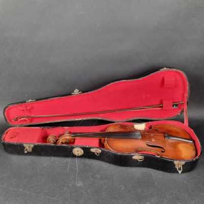 un vieil étui à violon contenant un violon, posé sur une surface noire