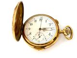 a gold pocket watch sitting on a white surface