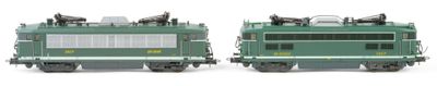 two green trains sitting side by side on a white surface