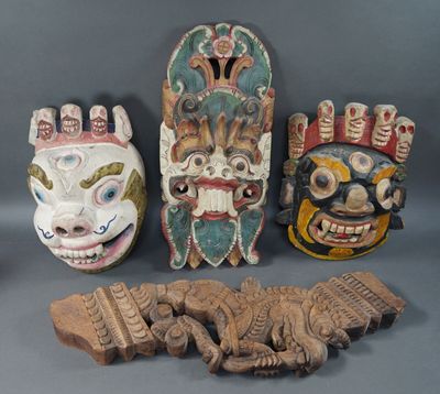 trois masques en bois sont posés les uns à côté des autres sur une surface grise