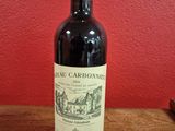 a bottle of red wine sitting on a wooden table