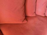 a pink couch with three pillows on top of it