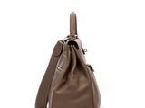 the large brown bag is sitting on the white surface