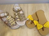 pair of gold and white sandals with a yellow bow tied to them