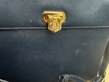 black leather purse with a gold lock on a wooden table