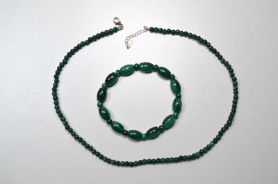 necklace and bracelet made of green glass beads on a white surface
