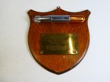 une plaque en bois sur laquelle repose un stylo et une plaque accrochée au mur