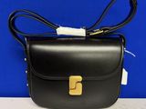 un sac en cuir noir orné d'une boucle dorée sur le devant