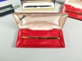 three pens and a pen case sitting on a table