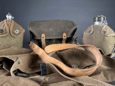 three flasks, a bag, and a bottle on a table