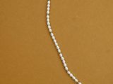 a white pearl beaded necklace on a brown background