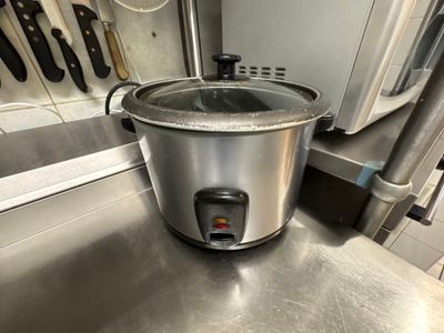 une mijoteuse argentée posée sur un plan de travail en inox