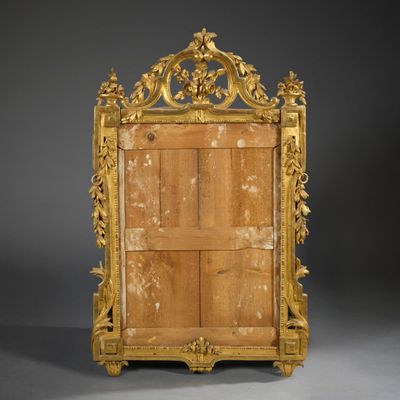 an ornately carved mirror with a wooden frame on a grey background