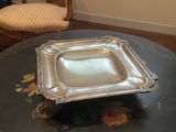 un plateau en argent posé sur une table, avec une chaise à l'arrière-plan