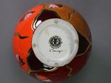 a red and orange ball with a white top on a gray surface